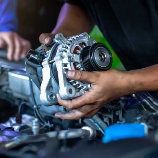 Mechanic handling a car alternator during repair